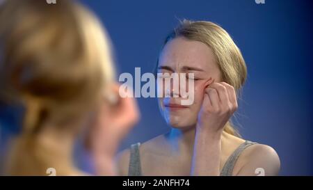 Weinend jugendlich weiblichen Desinfektion Gesicht Wunde im Spiegelbild suchen, Verzweiflung Stockfoto