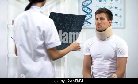 Patienten in Schaum zervikalen Kragen hören zu Arzt, x-ray Ergebnisse Stockfoto