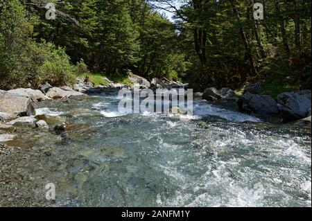 Wasser fließt unten einen sauberen, klaren Fluss in einem Tal Stockfoto