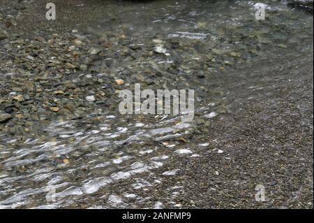 Graue Steine bilden das Bett eines seichten Fluss Stockfoto
