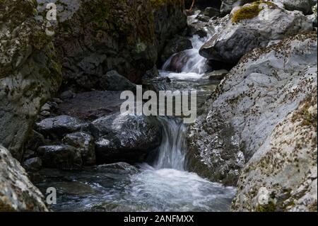 Ein fluss Kaskaden über Geröll, bilden kleine Wasserfälle entlang der Weise. Stockfoto