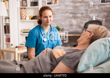 Weibliche Krankenschwester mit Stethoskop hören alte Frau Geschichte in einem Pflegeheim. Stockfoto