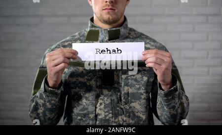 Rehab Wort auf Zeichen in den Händen der männlichen Soldaten geschrieben, Militär, Gesundheit Stockfoto