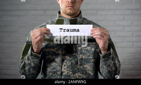 Trauma Wort auf Zeichen in den Händen der männlichen Soldaten geschrieben, Schäden an Körper, Gesundheit Stockfoto