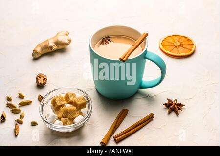 Traditionelle indische Masala Tee Chai mit Milch und Gewürzen auf weißem Hintergrund mit Zutaten oben Stockfoto