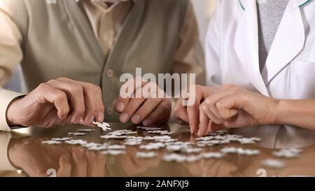 Weibliche Betreuer helfen, alter Mann tun puzzle Tabelle, Mentaltraining, Alzheimer Stockfoto
