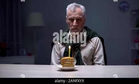 Traurig Opa feiert Geburtstag allein mit Stück Kuchen, das von der Familie vergessen Stockfoto