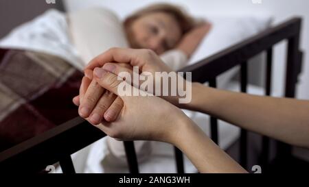 Tochter Unterstützung ihrer todkranken Mutter liegen auf Krankenhaus, Pflegeheim Stockfoto