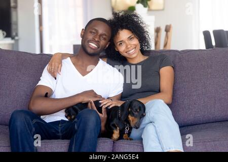Portrait von schwarz Paar mit niedlichen Hund auf der Couch entspannen Stockfoto