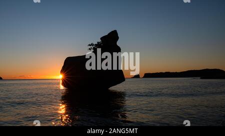 Silhouette Felsen bei Sonnenaufgang mit glänzenden Starburst in Cathedral Cove auf der Coromandel Halbinsel, Neuseeland Stockfoto