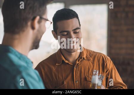 Freudige positiver Mann trinkt Bier mit seinem Freund Stockfoto