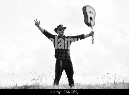 Inspiriert land Musiker. United mit der Natur. Stattlicher Mann mit Gitarre. Country Music Konzept. Gitarrist Land Sänger stand im Feld Himmel Hintergrund Stockfoto