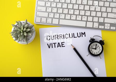 Lebenslauf mit Tastatur und Uhr auf gelbem Hintergrund Stockfoto