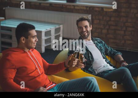 Positive freudige männliche Freunde jubeln mit einer Flasche Bier Stockfoto