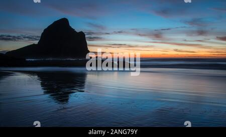 Felsen Silhouette in Piha Strand bei Sonnenuntergang, West Auckland, Neuseeland Stockfoto