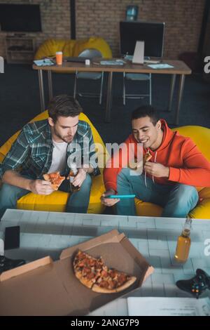 Blick von oben auf die freudige junge Männer essen Pizza Stockfoto