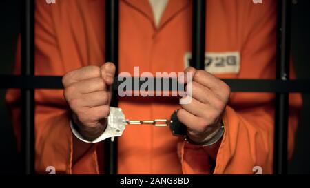Gefangene, die Hände in den Handschellen, gefährliche Kriminelle hinter Bars Stockfoto