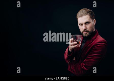 Stattliche reifer Mann in Weinigen Jacke mit Whiskey Toasten Stockfoto