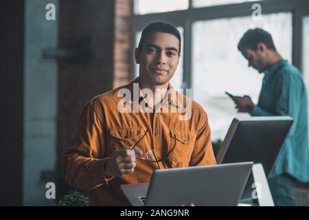 Freundliche nette Mann seine Brille in der Hand halten Stockfoto