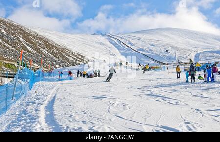 Männer, Frauen und Kinder auf sonnigen Schneepisten im Cairngorm Mountain Ski Center Cairngorms National Park, Aviemore, Scottish Highlands, Schottland UK Stockfoto