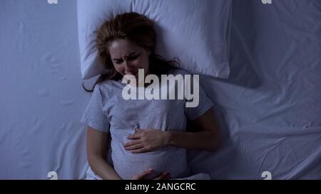 Lonely erwartet Frau im Bett weinen, holding Bauch, Hoffnungslosigkeit und Depressionen Stockfoto