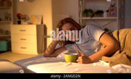 Entspannt glücklich Frau trinkt Kaffee im Bett liegt, am Wochenende morgens, Frieden Stockfoto