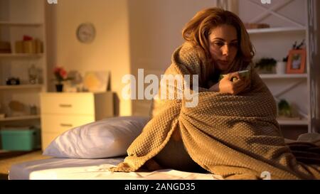 Kranke Frau in der Decke trinken heißen Tee sitzen auf dem Bett, health care Virus abgedeckt Stockfoto