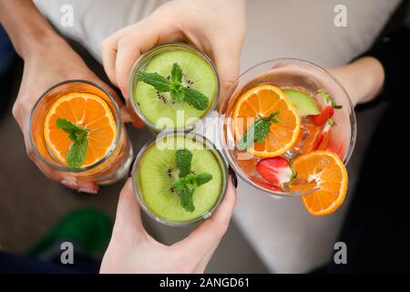 Zitrusfrüchte in einem Glas Wasser. Erfrischende Getränke in der Hand des Mannes. Scheiben von hellen, frischen Obst. Stockfoto