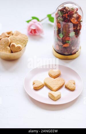 Herzförmige butter Cookies auf ein rosa Platte und Rose auf den Tisch. Valentines Tag Konzept Stockfoto