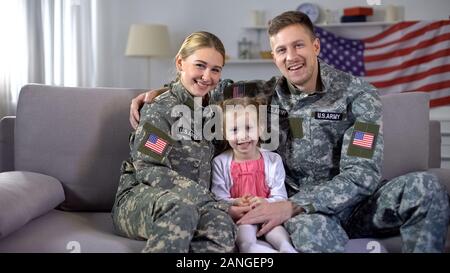 Uns militärische Familie Schmusen auf dem Sofa bei camera Nation und Patriotismus lächelnd Stockfoto