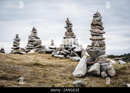 Einige Man-made Granit Stapel (Cairns) auf dem Küstenweg in der Bretagne, Frankreich, an einem bewölkten Tag. Stockfoto