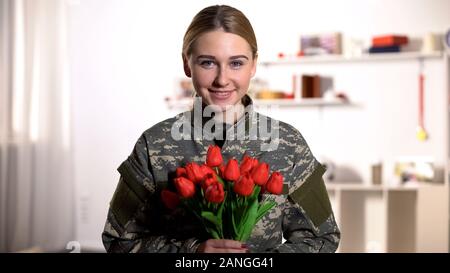 Lächelnd weibliche militärischen Holding Tulpen Bouquet und Kamera, 8. März Stockfoto
