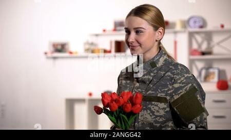 Freudige weiblichen Sergeant jubel Tulpen Bouquet und lächeln Heimkehr nach dem Krieg Stockfoto