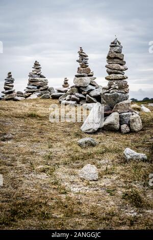 Einige Man-made Granit Stapel (Cairns) auf dem Küstenweg in der Bretagne, Frankreich, an einem bewölkten Tag. Stockfoto