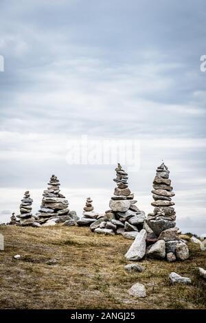 Einige Man-made Granit Stapel (Cairns) auf dem Küstenweg in der Bretagne, Frankreich, an einem bewölkten Tag. Stockfoto