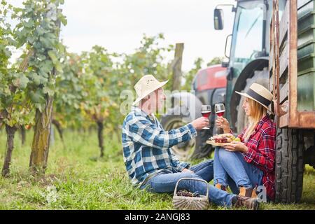 Paar trinken romantische Wein im Weinberg während der Weinlese neben einem Traktor Stockfoto