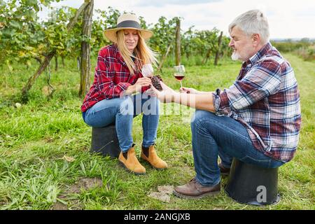 Winzer paar Getränke ein Glas Rotwein zusammen im Weinberg während der Weinlese Stockfoto
