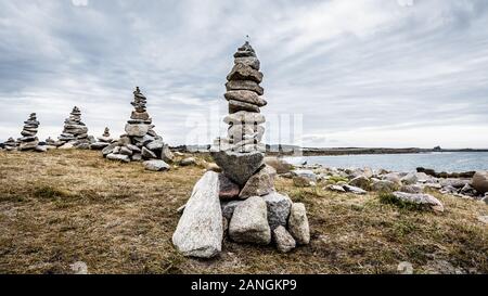 Einige Man-made Granit Stapel (Cairns) auf dem Küstenweg in der Bretagne, Frankreich, an einem bewölkten Tag. Stockfoto