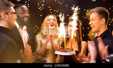 Hübsche Frau in der Partei hat der Kuchen mit Feuer Kerzen, feiert Geburtstag Stockfoto