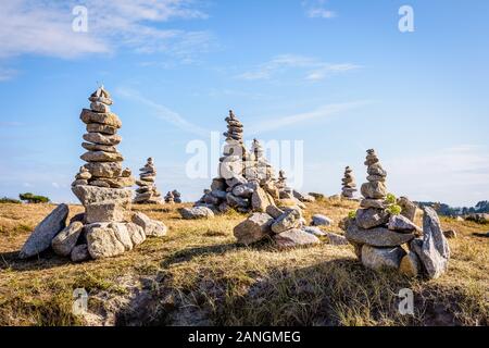 Vielen Man-made Granit Stapel (Cairns) auf dem Küstenweg in der Bretagne, Frankreich, an einem sonnigen Nachmittag. Stockfoto