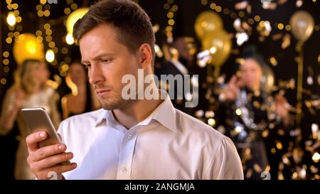 Junger Mann messaging Smartphone bei Party closeup, Bestellung taxi nach Anwendung Stockfoto