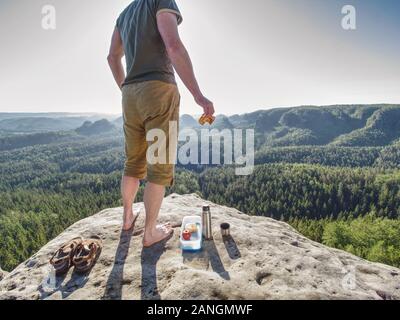 Sportler bei einem Picknick in der Wüste. Schinken Toasts und Apple in einem kleinen und Kaffee in der Flasche für Frühstück. In der Rückseite größer Wälder hill Co Stockfoto