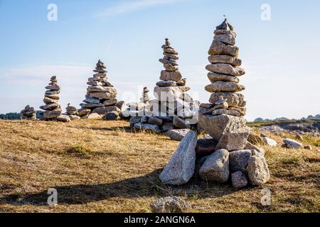 Vielen Man-made Granit Stapel (Cairns) auf dem Küstenweg in der Bretagne, Frankreich, an einem sonnigen Nachmittag. Stockfoto