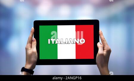 Weibliche Hände, die Tablette mit italienischen Wort gegen die nationale Flagge, online App Stockfoto