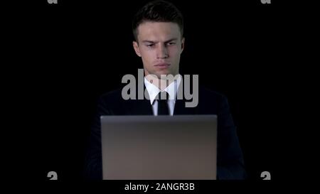 Ernsthafte Geschäftsmann Arbeiten am Laptop gegen den dunklen Hintergrund, Vertrauen Stockfoto