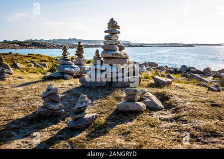 Vielen Man-made Granit Stapel (Cairns) auf dem Küstenweg in der Bretagne, Frankreich, an einem sonnigen Nachmittag. Stockfoto