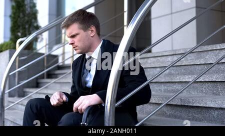 Unglücklich männliche Gesellschaft manager Sitzung außerhalb der Gebäude, Entlassung Verzweiflung Stockfoto