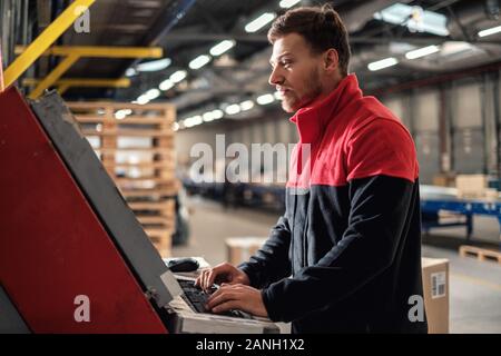 Kurier holt Paket auf einem Lager Stockfoto