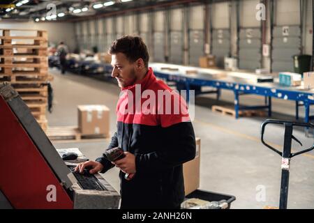Kurier holt Paket auf einem Lager Stockfoto