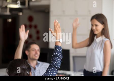 Weibliche tausendjährigen Teamleiter halten motivationale Meeting mit Kollegen im Büro, diverse Mitarbeiter in Teambuilding Aktivität Hände heben engagiert voti Stockfoto